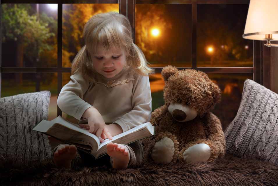 Picture of a girl reading to her teddy bear